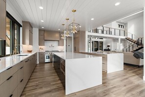 A modern kitchen with a large island, built-in appliances, and a mezzanine level with a staircase.
