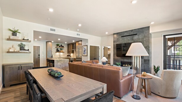 Una cocina moderna con electrodomésticos integrados, un comedor con mesa y sillas de madera, y una zona de estar acogedora con sofá y sillones.