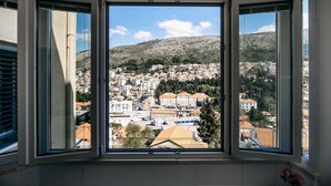 Une pièce dotée d’une grande fenêtre donnant sur une ville avec ses bâtiments et une colline.