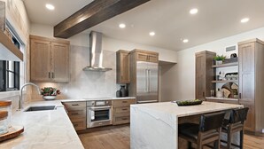Une cuisine moderne avec des meubles en bois, des appareils en acier inoxydable et un îlot central en marbre.
