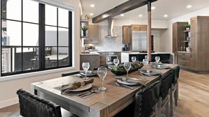 Une cuisine moderne avec des meubles en bois, un grand îlot central aménagé en coin repas et une vue dégagée grâce à une grande fenêtre.