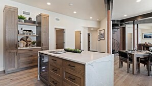 Une cuisine moderne avec des meubles en bois, un plan de travail en marbre et un coin repas comprenant une table et des chaises.