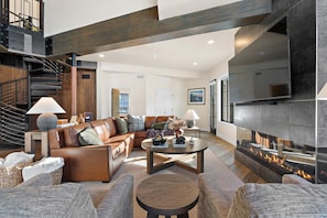 Una sala de estar moderna con chimenea, sofá de cuero y una escalera.