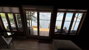 A room with a view of a lake, a sofa, a chair, and a small table. - Red Cedar Haven Lakefront Dock  Kayaks (Sidney)