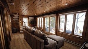 A wooden interior with a sofa, a staircase, and large windows. - Red Cedar Haven Lakefront Dock  Kayaks (Sidney)