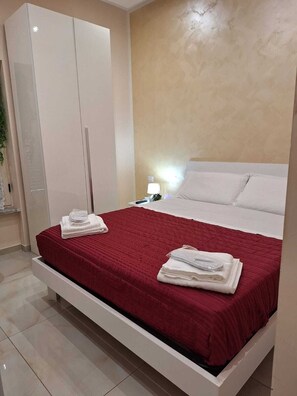 A modern bedroom with a large bed, white linens, a red bedspread, and a wardrobe. - Pompei 79 AD b&b (Scafati)
