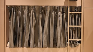 A room with a large, metallic curtain covering a window. - Bed & Bread Dormitory (Bharuch)