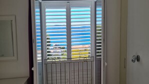 A room with a sliding glass door featuring horizontal blinds, a metal gate, and a view of buildings outside. - Holiday Home Mico (Gradac)