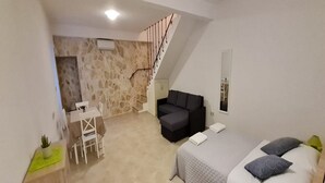 A compact room with a bed, a sofa, a small table, and a chair. There is a staircase leading to an upper level. - Holiday Home Mico (Gradac)