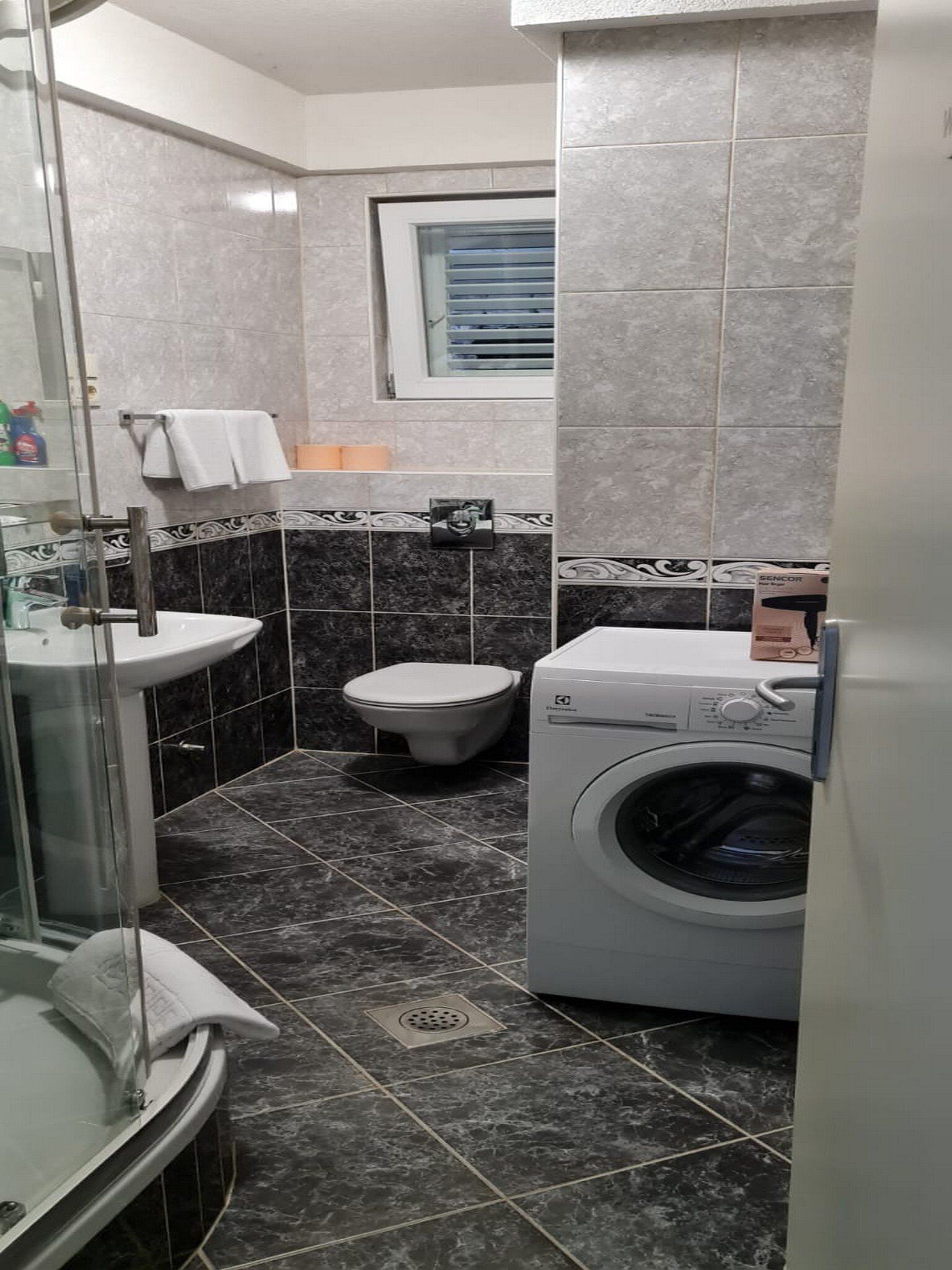 A compact bathroom with a sink, toilet, and washing machine.