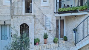 A stone building with a staircase leading to a balcony with potted plants. - Holiday Home Mico (Gradac)