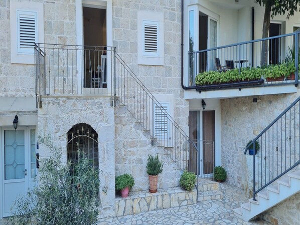 A stone building with a staircase leading to a balcony with potted plants. - Holiday Home Mico (Gradac)