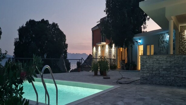A pool area with stone flooring, a metal pool ladder, and a stone wall. - Holiday Home Mico (Gradac)