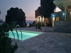 Un espace piscine doté d’un sol en pierre, d’une échelle de piscine en métal et d’un mur en pierre.