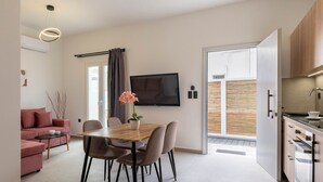 Un appartement moderne comprenant un coin repas, un salon avec un canapé, une cuisine et un téléviseur fixé au mur.