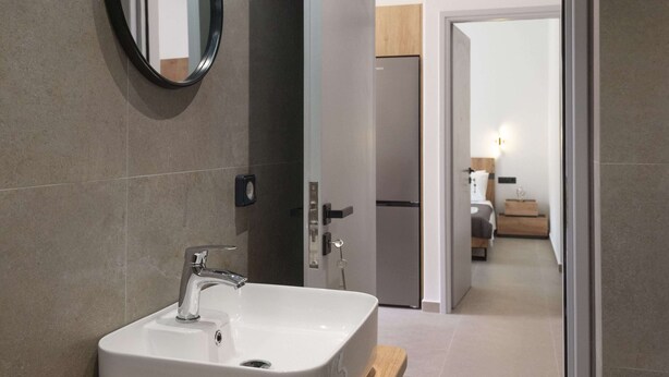 Une salle de bain moderne avec un lavabo rectangulaire, un miroir rond et un luminaire placé au-dessus du miroir.