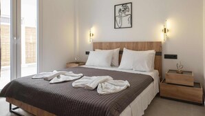 Une chambre moderne avec un grand lit, deux tables de chevet, une œuvre d’art accrochée au mur et un luminaire fixé au plafond.