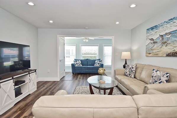 A modern living room with a TV, sofa, coffee table, and a painting on the wall.