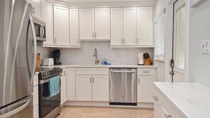 Una cocina moderna con armarios blancos, electrodomésticos de acero inoxidable y una salpicadera de azulejos.