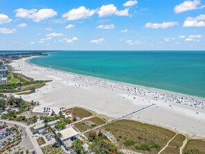 Vista aerea di una spiaggia con una lunga passeggiata, edifici e un'area di parcheggio.