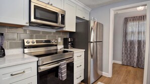 Eine moderne Küche mit Edelstahlgeräten, darunter Mikrowelle, Backofen und Kühlschrank.