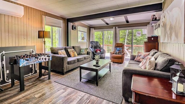 A spacious living room with a foosball table, sofas, and a coffee table. - Spa - Waterfront - Babyfoot | La Source (Saint-Côme)