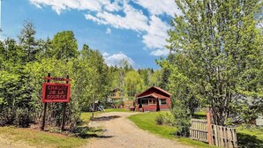 A wooden cabin with a red roof, surrounded by trees and a dirt path leading to it. - Spa - Waterfront - Babyfoot | La Source (Saint-Côme)