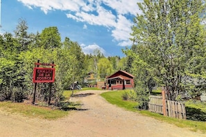 A wooden cabin with a red roof, surrounded by trees and a dirt path leading to it. - Spa - Waterfront - Babyfoot | La Source (Saint-Côme)