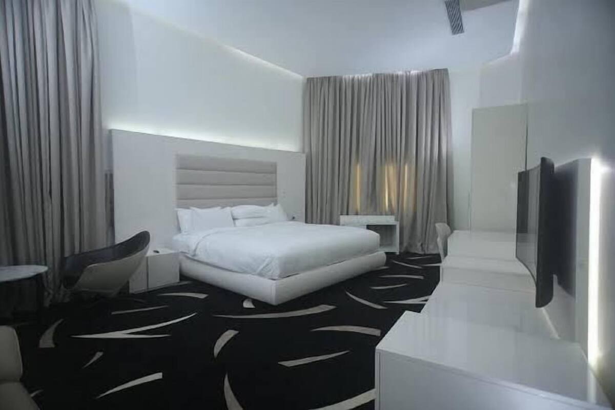 A modern hotel room with a large bed, a flat-screen TV, and a desk.