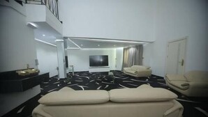 Una sala de estar moderna con una alfombra estampada en blanco y negro, un televisor de pantalla plana grande, un sofá beige y un sillón beige.