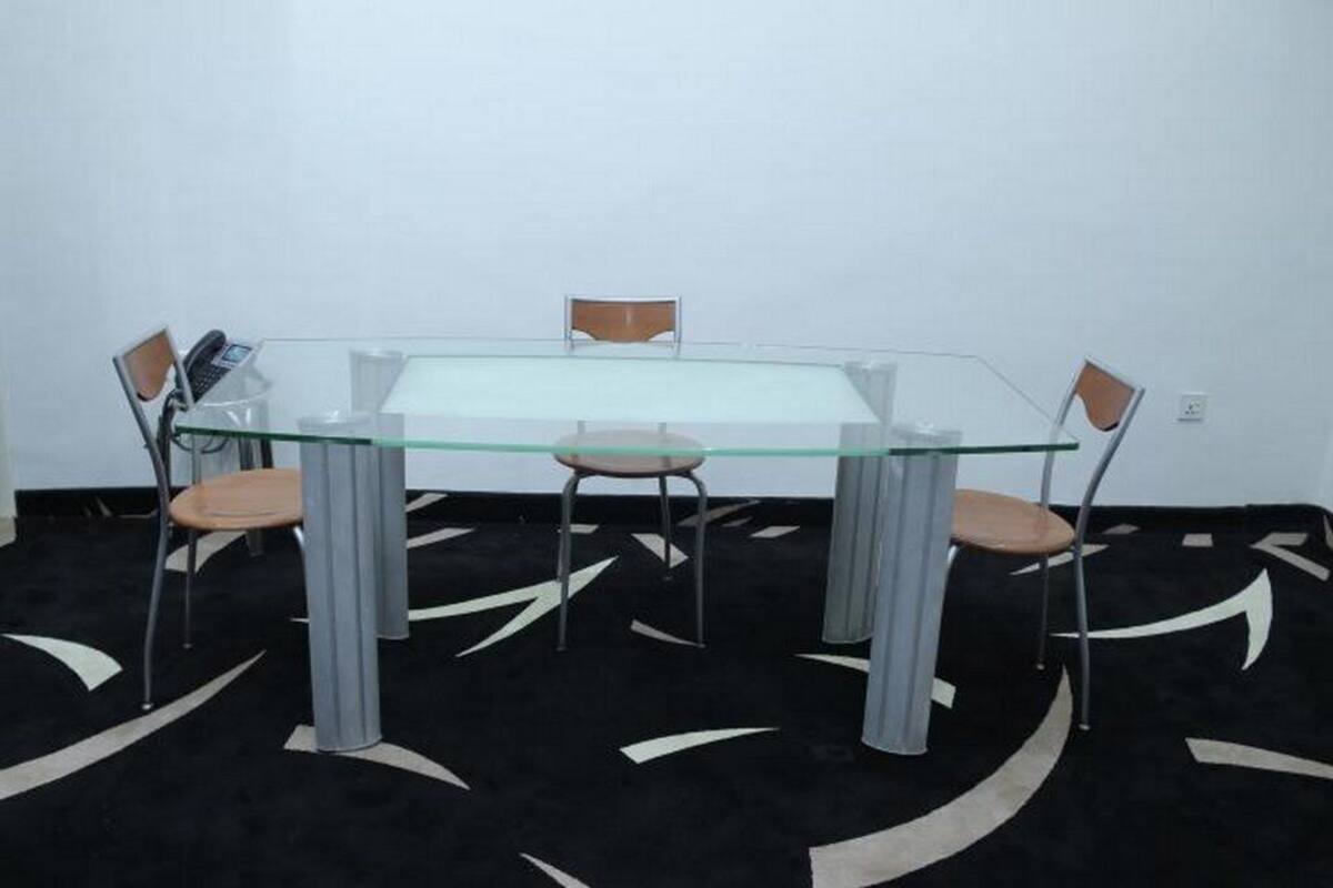 A glass-top table with four chairs, a telephone, and a small table lamp.