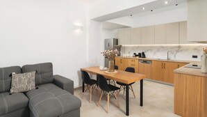 Una cocina moderna con armarios de madera, encimera de mármol y comedor con mesa de madera y sillas negras.
