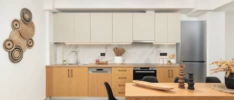 Una cocina moderna con armarios de madera, salpicadero de mármol y un refrigerador de acero inoxidable.