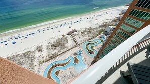 A resort with a beach, a pool area, and a building with large windows. - New Complex!  BeachFront!  Lazy River/Slide!! (Orange Beach)