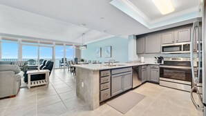 A modern kitchen with a large island, stainless steel appliances, and a view to the outside. - New Complex!  BeachFront!  Lazy River/Slide!! (Orange Beach)