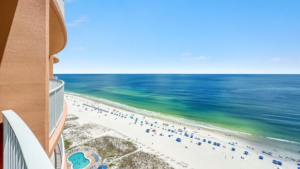A beach view from a balcony with a pool and beach umbrellas. - New Complex!  BeachFront!  Lazy River/Slide!! (Orange Beach)