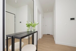 A hallway leading from the living area, decorated with a slim console table and a vase of fresh tulips. - Warsaw | Domaniewska 24 | Stylish Apartment with Parking | Air Conditioning (Warszawa)