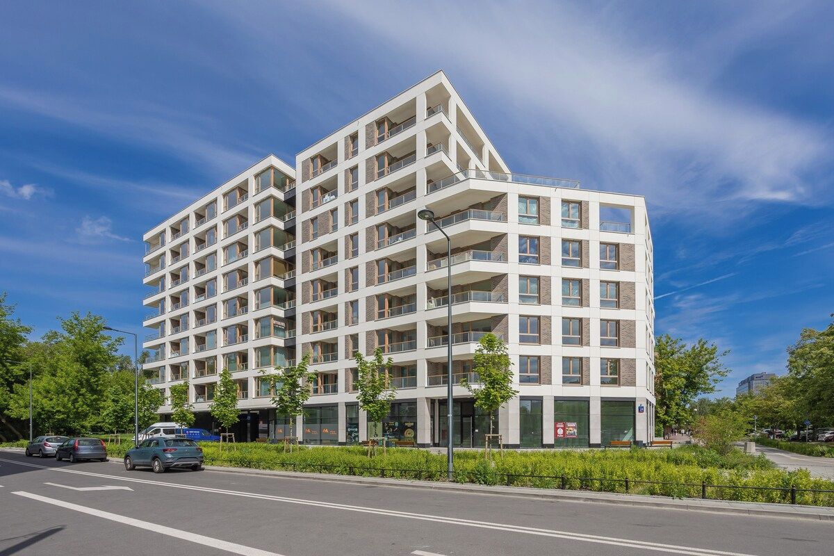 A multi-story residential building with balconies, a flat facade, and a clear sky.