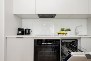 A compact kitchenette equipped with a coffee machine, kettle, and minimalist countertop accessories. - Warsaw | Domaniewska 24 | Stylish Apartment with Parking | Air Conditioning (Warszawa)