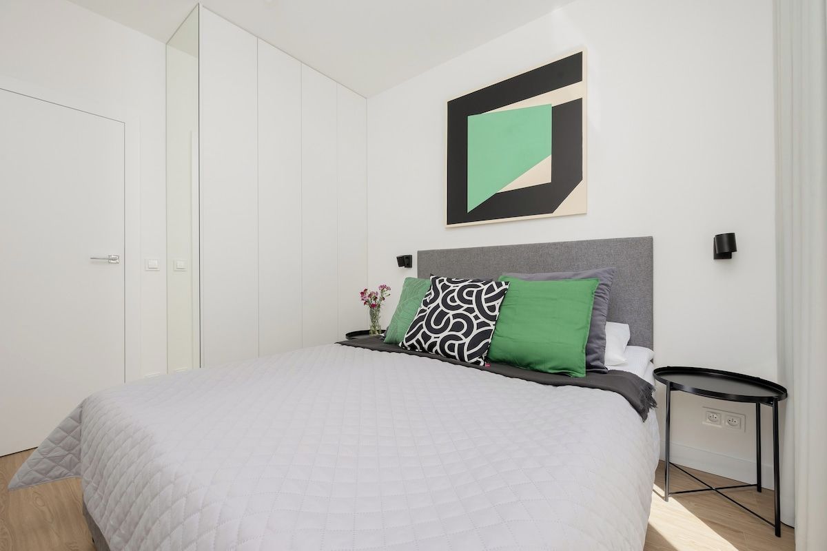 Een moderne slaapkamer met een bed, nachtkastje en wanddecoratie.