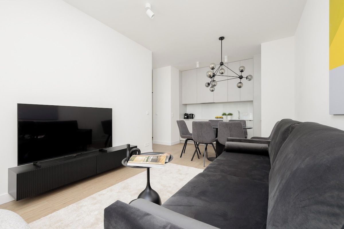 Un salon moderne doté d’un téléviseur à écran plat, d’un canapé et d’un coin repas avec des chaises et une table.