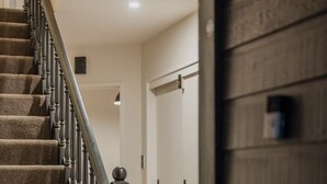 A staircase with carpeted steps and a wooden handrail, leading to a room with a wooden floor and a door.