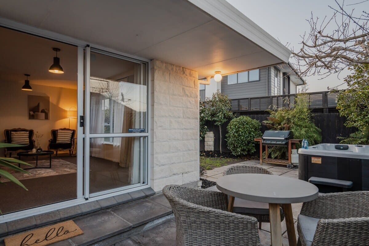 A patio with wicker furniture, a grill, and a hot tub.