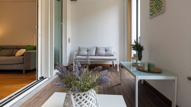 A modern living room with a grey sofa, a white coffee table, and a wooden floor.