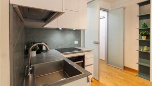 A modern kitchen with a stainless steel sink, a built-in oven, and a sleek backsplash.