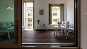 A modern apartment with a balcony, a dining area, and a living room with a sofa.