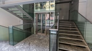A modern interior with a glass railing staircase leading to an upper level.