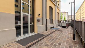 A building with a yellow facade, a glass entrance, and a tiled walkway.