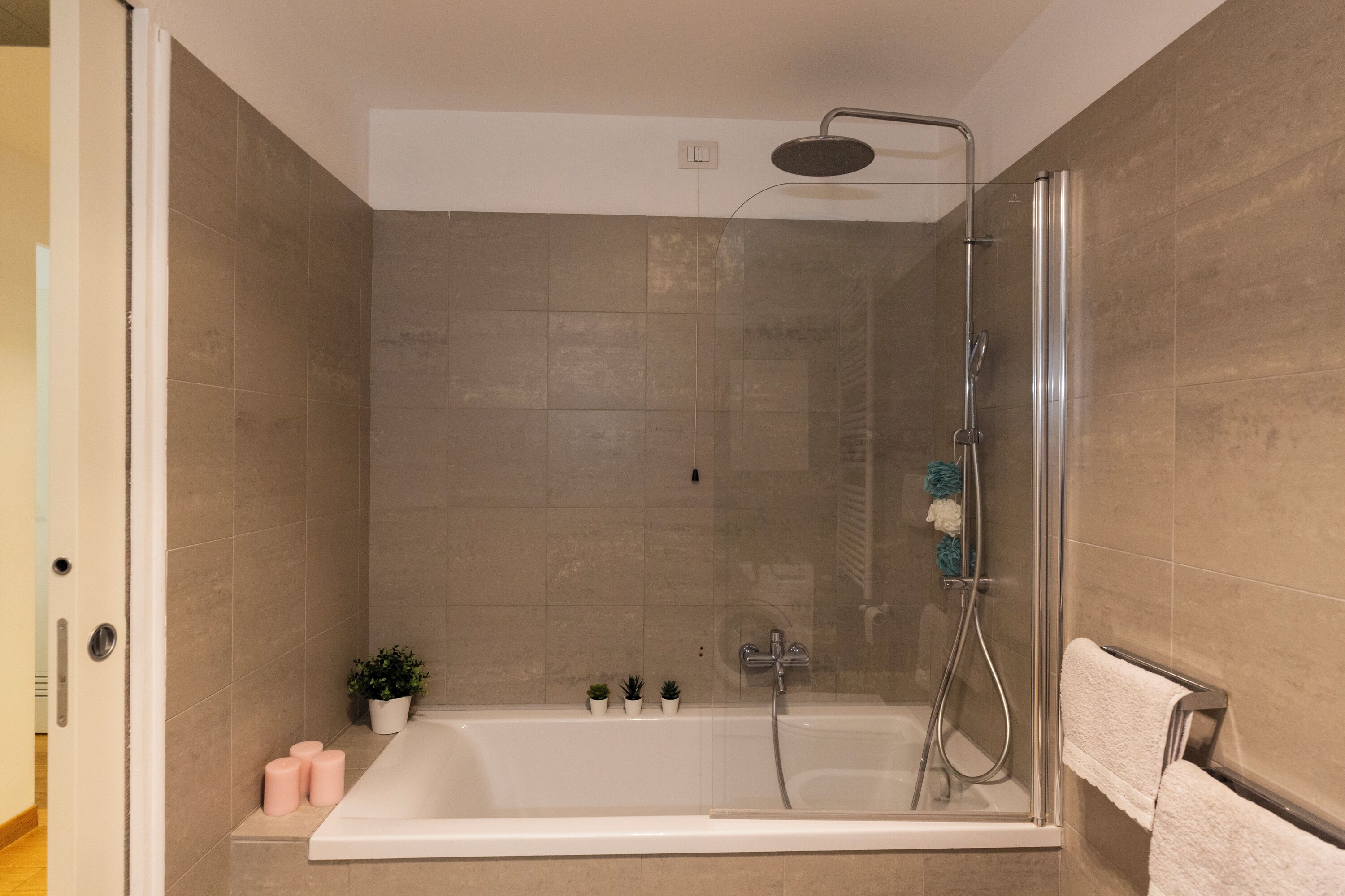 A modern bathroom with a bathtub, shower, and glass enclosure.