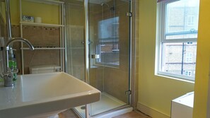 A bathroom with a shower, a sink, and a window. - 4 Bed House London Hammersmith Fulham Short Let (London)
